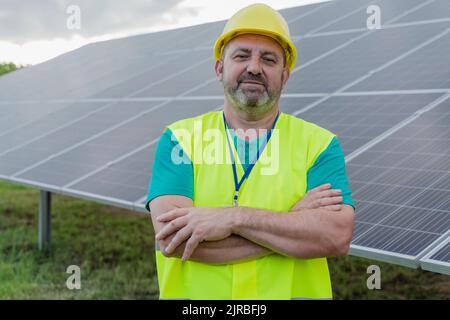 Smiling engineer standing with arms crossed at solar station Stock Photo