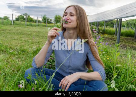 Engineer smelling flower on field at solar power station Stock Photo