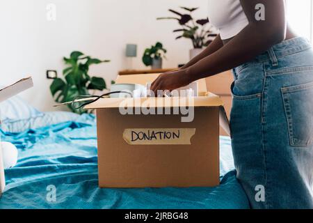 Woman packing donation box on bed at home Stock Photo