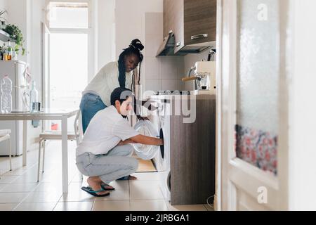 Smiling woman with roommate doing laundry at home Stock Photo