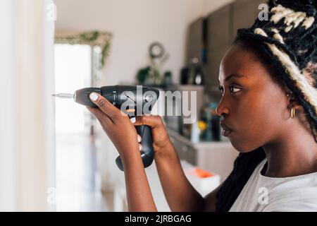 Craftswoman using drill at home Stock Photo