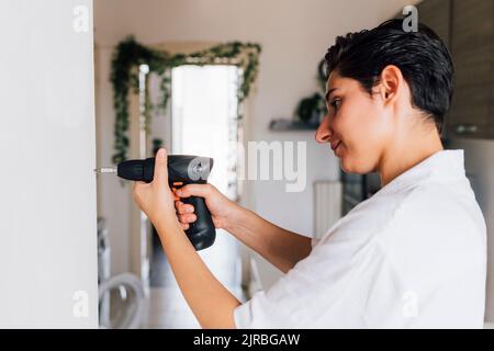 Young craftswoman using drill at home Stock Photo