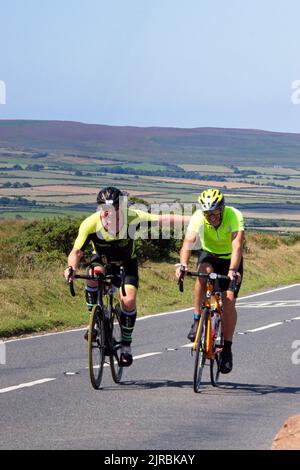 7thAug22 Gower Swansea Wales UK Triathlon Ironman cycling event Pair of cyclists side by side one giving encouragement to fellow competitor Stock Photo