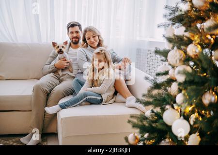 Happy family: mom, dad and pet. Family in a bright New Year's interior ...