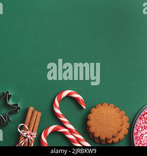 Holiday food and seasonal decorations from above. Green Christmas square background with copy space. Stock Photo