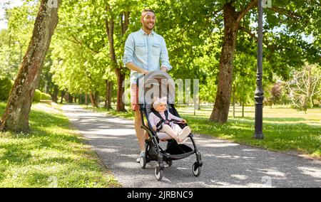 happy father with child in stroller at summer park Stock Photo