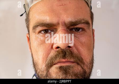 Selective focus, close up shot of sweaty, exhausted man face with safety equipment marks. Stock Photo