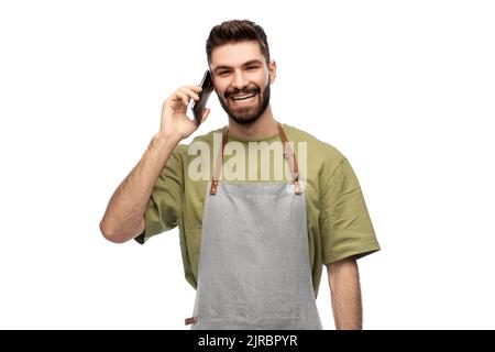 happy barman in apron calling on smartphone Stock Photo