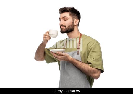 happy barista or waiter in apron drinking coffee Stock Photo