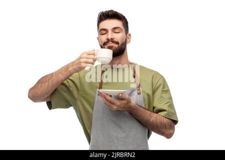 happy barista or waiter in apron drinking coffee Stock Photo