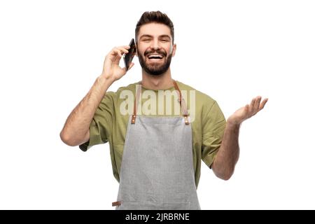 happy barman in apron calling on smartphone Stock Photo