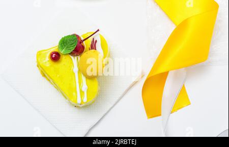 lemon yellow heart cake with cherries and cream on white background Stock Photo