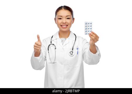 asian female doctor with pills showing thumbs up Stock Photo