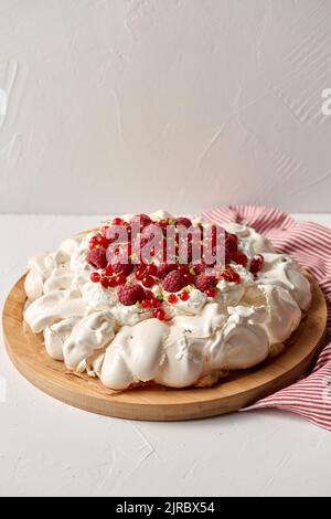 pavlova meringue cake with berries on wooden board Stock Photo