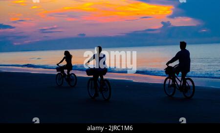 Family riding bikes on the beach on Hilton Head SC , sunrise. Stock Photo