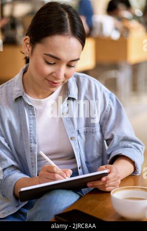 Young Asian woman student using digital tablet for elearning. Stock Photo