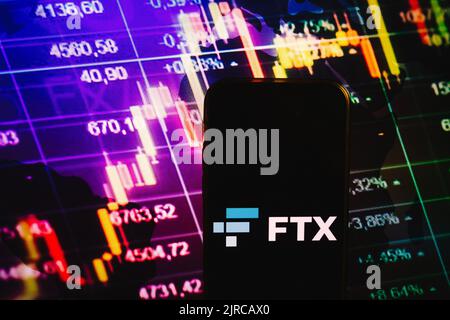 KONSKIE, POLAND - August 10, 2022: Smartphone displaying logo of FTX cryptocurrency exchange on stock exchange diagram background Stock Photo