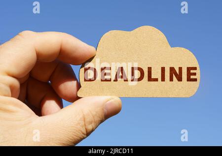 Against the background of the sky in the hands of a man, a figure of a cloud with the inscription - Deadline. Technology and business concept. Stock Photo