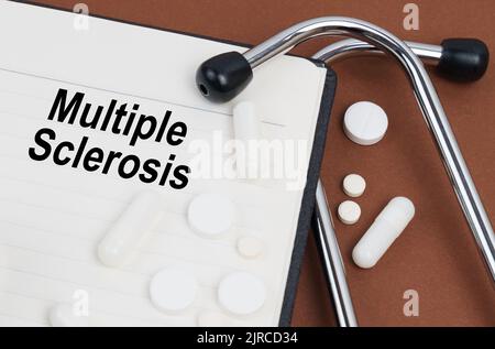 Medical concept. On a brown surface lies a stethoscope, pills and a notepad with the inscription - Multiple Sclerosis Stock Photo