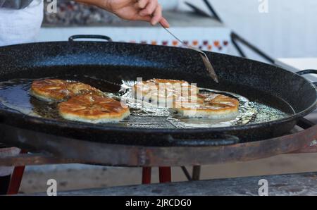 Cook roasts flour pastries in a large pan with butter outdoor Stock Photo