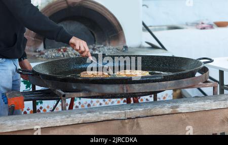 Cook roasts flour pastries in a large pan with butter outdoor Stock Photo