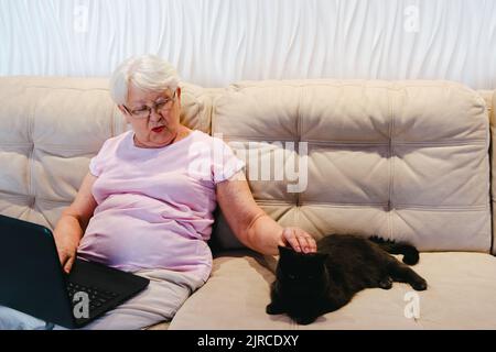 happy elderly woman using laptop computer at home. Senior mature older woman watching business training, online webinar on laptop computer remote work Stock Photo