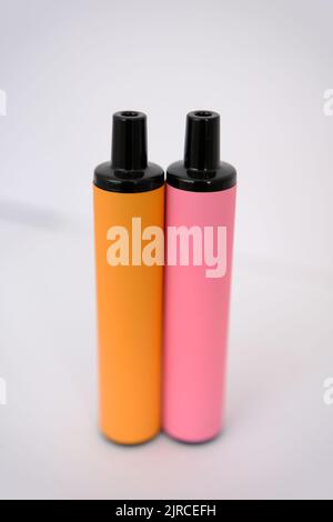 pink and orange disposable electronic cigarettes on white background. Copy space. Stock Photo