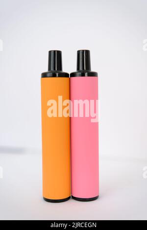 pink and orange disposable electronic cigarettes on white background. Copy space. Stock Photo
