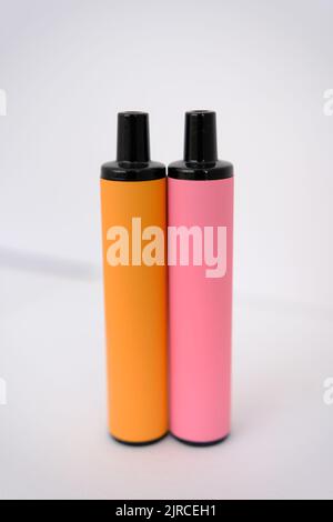 pink and orange disposable electronic cigarettes on white background. Copy space. Stock Photo