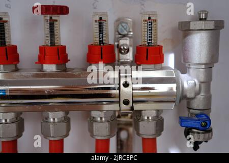 Heating system manifold valves for heat flooring and water supply in a country house. Pipes collector in a building under construction. Stock Photo