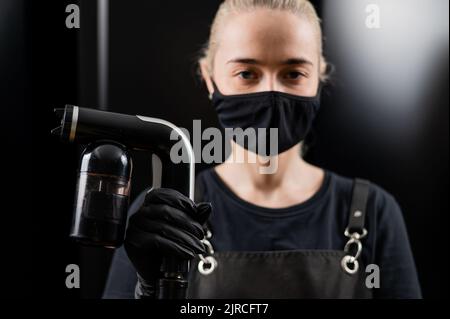 The master of instant tanning holds a spray pen with lotion. Express tan in a beauty salon. Stock Photo