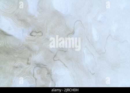 Natural, abstract blue and beige background. Wet beach sand texture  with swirling waves. Top view. Stock Photo