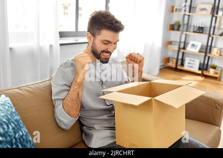 happy smiling man with open parcel box at home Stock Photo