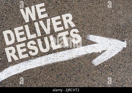 Business concept. On the asphalt road markings an arrow with the inscription - WE DELIVER RESULTS Stock Photo