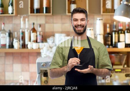 barman in apron with glass of cocktail at bar Stock Photo