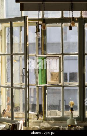 Old window frame painted in white color with stained glass and light bulbs hanging on ceiling Stock Photo