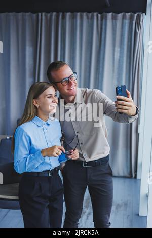 Happy business colleagues working together in the office and using the phone. Colleagues take a selfie during a break Stock Photo