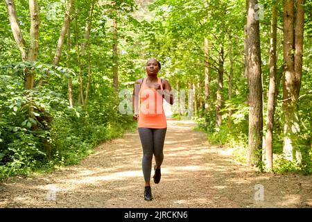 young african american woman running in forest Stock Photo