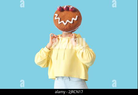 Woman with funny monster cookie instead of her head on light blue background. Halloween celebration Stock Photo