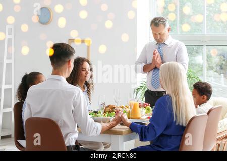 Family praying before having festive dinner on Thanksgiving Day Stock Photo