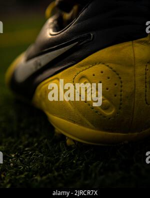 A vertical closeup shot of a yellow Nike Ctr360 Maestri Soccer Shoe in the field Stock Photo