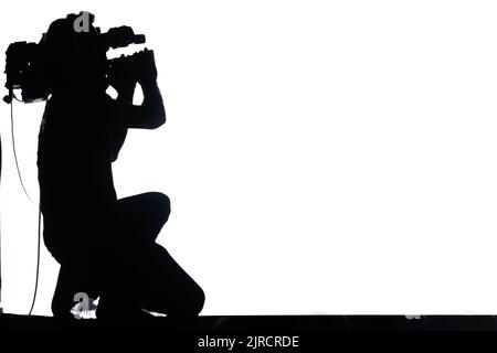 Videographer profession. Silhouette of a man with a camera who shoots a video on a white background Stock Photo