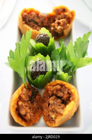 Stuffed meatballs (Turkish: Icli Kofte) with olives on the dinner plate. Stock Photo