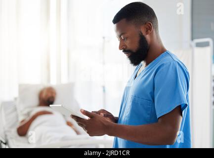 Black doctor using a digital tablet while working with sick patients at a hospital, serious and thinking. African American health care worker using Stock Photo