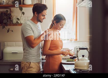 Romantic, caring and loving young couple supporting each other while preparing a meal in the kitchen. Man and woman in a happy, stressless and relaxed Stock Photo