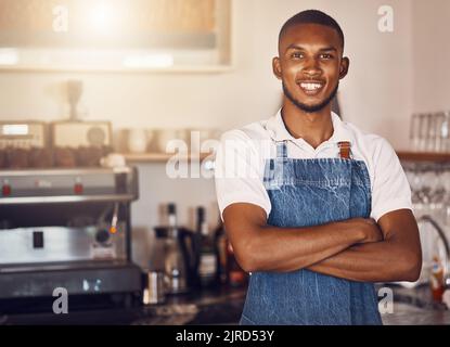 Business owner standing with arms crossed at a cafe, showing pride and success working at a restaurant. Portrait of a waiter, employee or worker Stock Photo