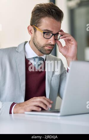 Hard work makes millions. a businessman using a laptop at his office desk. Stock Photo