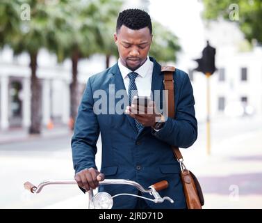Reading, texting or web search on a phone of a business man ready to ride a bike to work or home. Digital entrepreneur using 5g internet on modern Stock Photo