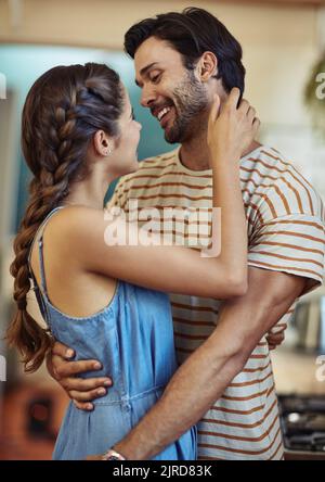 I just want you close to me. an affectionate young couple embracing in their kitchen at home. Stock Photo