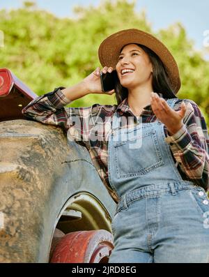 Agriculture, sustainability and farmer talking on phone while working on a farm with a tractor. Wellness, health and agro woman networking with a Stock Photo